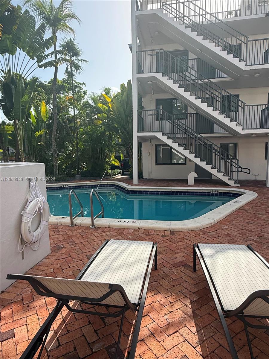 A swimming pool sits on a brick patio next to a multi-story apartment building — 2924 Day Ave # N110, Miami FL 33133, MIAMI, FL