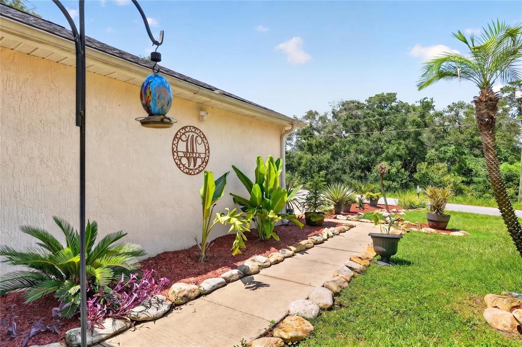 A concrete walkway leads along the side of a house with landscaping and a palm tree — 6 OAK CIRCLE COURSE, OCALA, FL