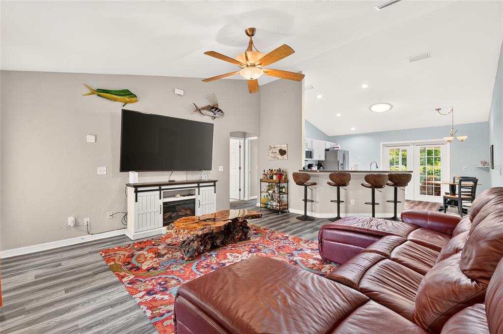 A living room with a large television, leather sectional, and a natural wood coffee table — 6 OAK CIRCLE COURSE, OCALA, FL