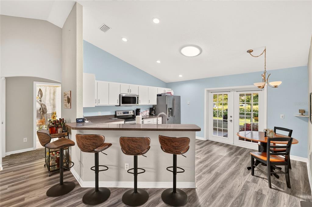 A kitchen with white cabinets, a breakfast bar with stools, and a dining area — 6 OAK CIRCLE COURSE, OCALA, FL