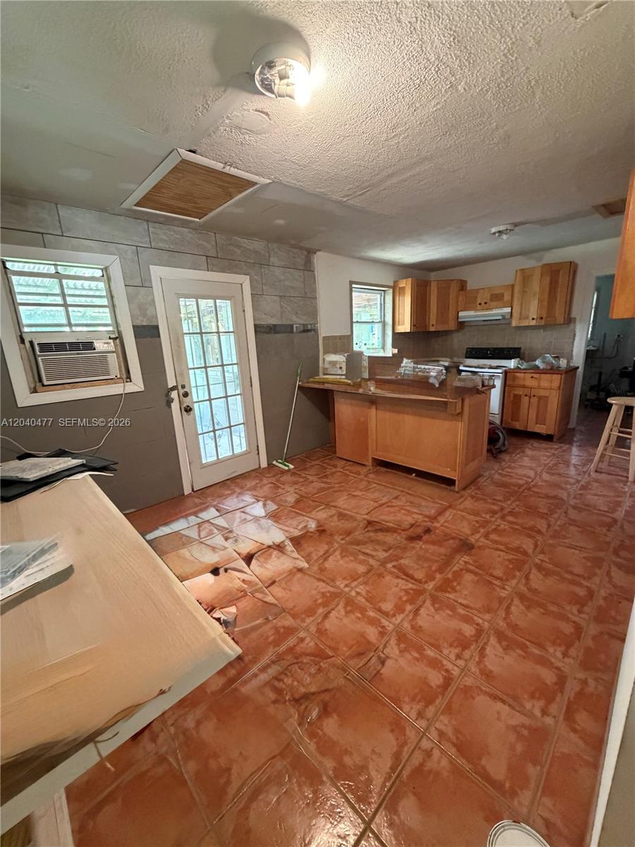 A kitchen with terracotta tile flooring, wooden cabinets, and a glass-paned exterior door — 9110 SW 44th St, Miami FL 33165, MIAMI, FL