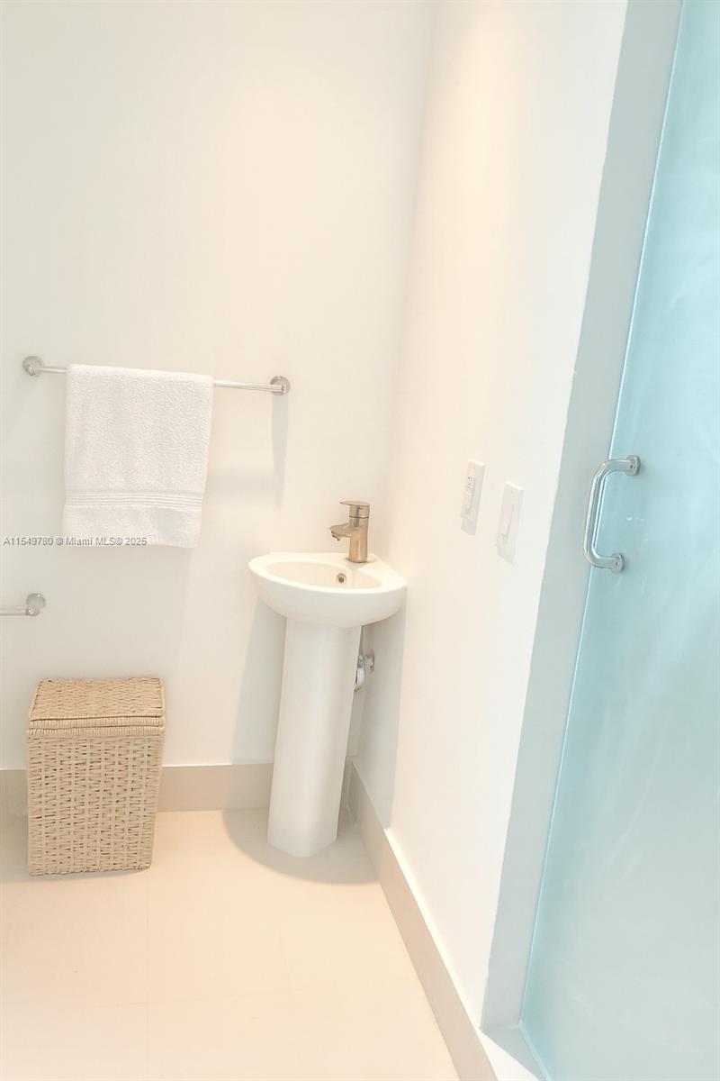 A small bathroom features a white pedestal sink, a towel rack, and a wicker hamper — 501 NE 31st St # 3004, Miami FL 33137, MIAMI, FL