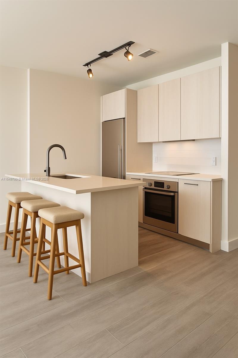 A modern kitchen features light wood cabinetry, stainless steel appliances, and a breakfast bar island — 501 NE 31st St # 3004, Miami FL 33137, MIAMI, FL