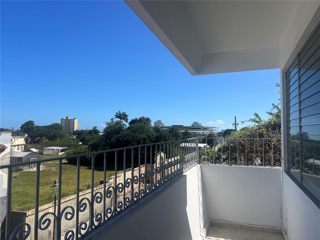 An outdoor balcony features a metal railing overlooking a grassy lot and distant buildings — 503 CARR MAYOR CANTERA STREET, PONCE, PR