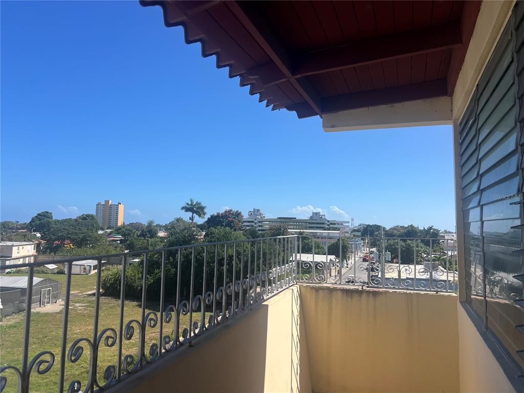 A balcony with a metal railing overlooks a town with buildings and trees under a sky — 503 CARR MAYOR CANTERA STREET, PONCE, PR