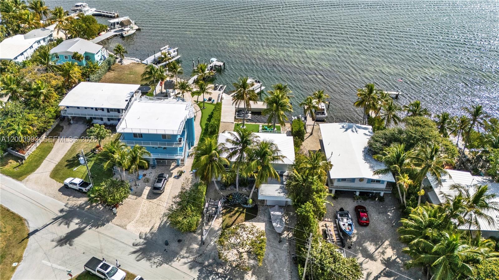 An aerial view shows several waterfront houses with docks, palm trees, and parked vehicles — 69 Shoreland Dr, Key Largo FL 33037, KEY LARGO, FL