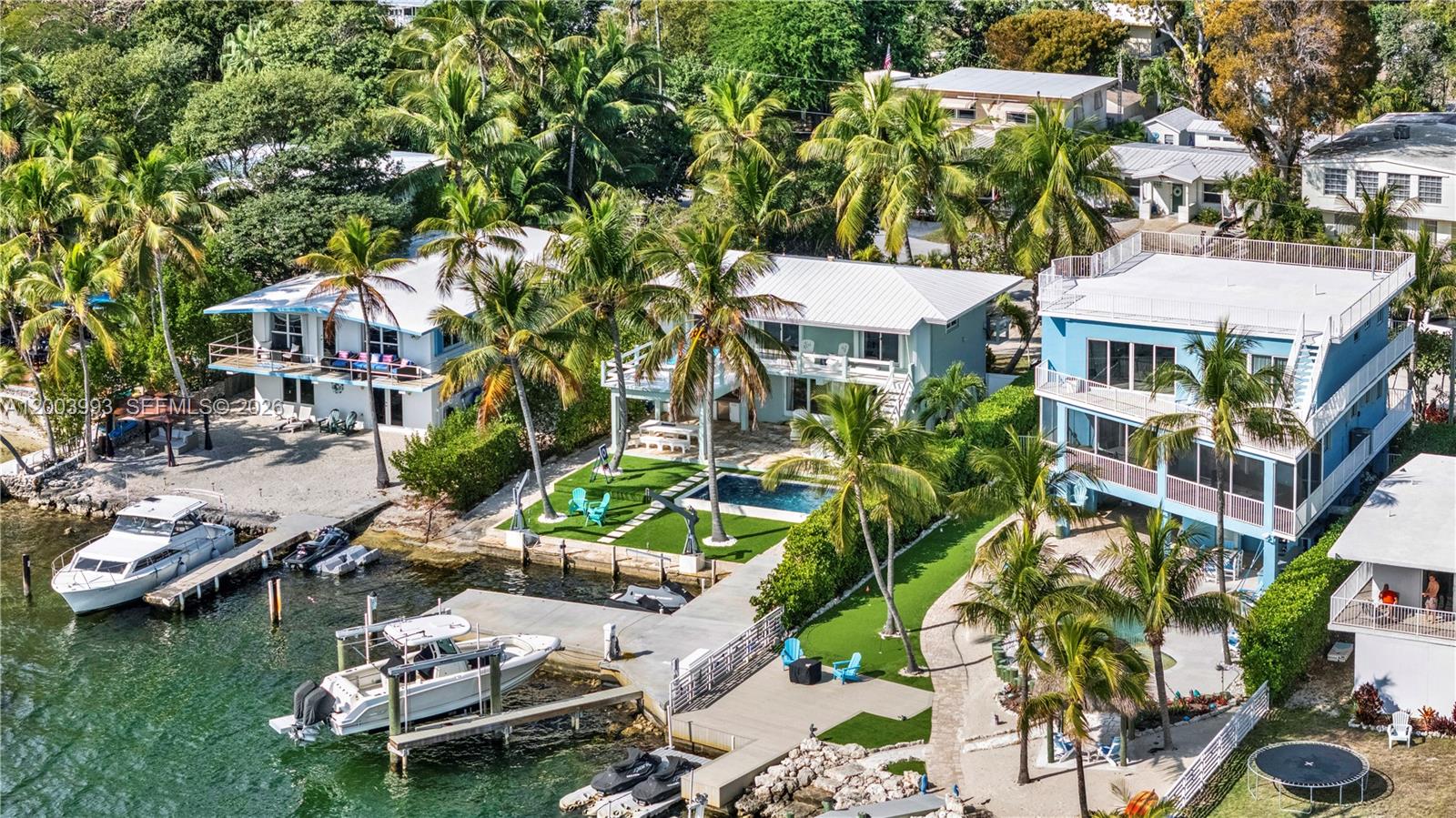 An aerial view shows three waterfront houses with docks, boats, and a swimming pool — 69 Shoreland Dr, Key Largo FL 33037, KEY LARGO, FL