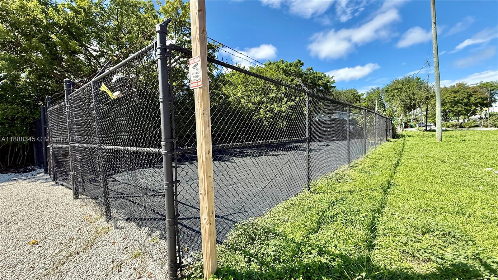 A fenced-in paved area is surrounded by trees and a grassy lawn — 6050 N Miami Ave, Miami FL 33137, MIAMI, FL