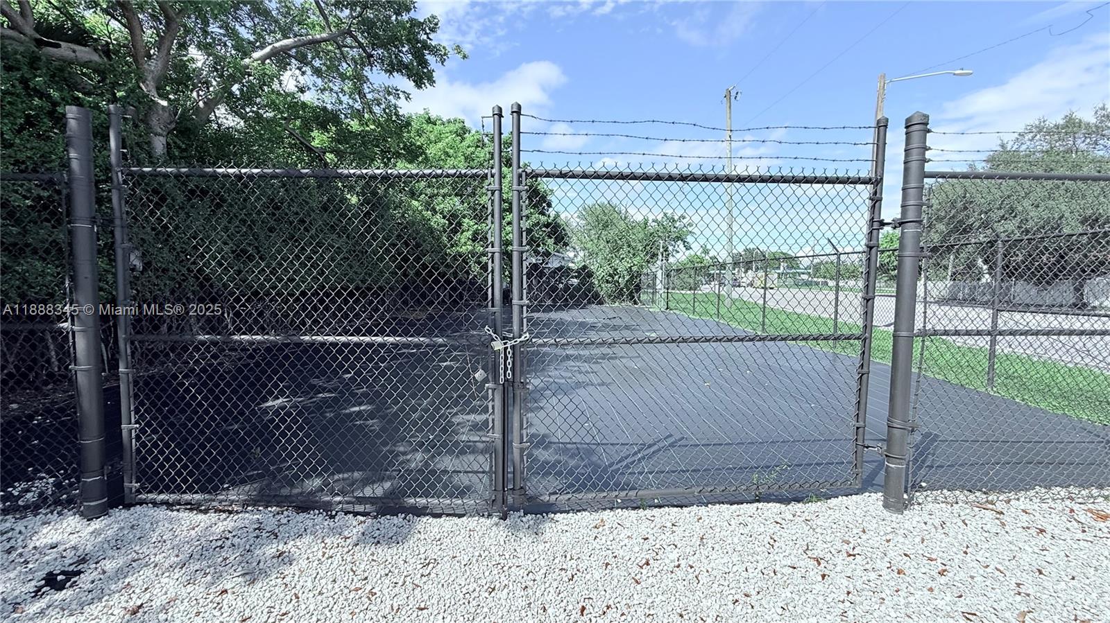 A chain-link fence with a locked gate encloses a paved lot covered in gravel — 6050 N Miami Ave, Miami FL 33137, MIAMI, FL