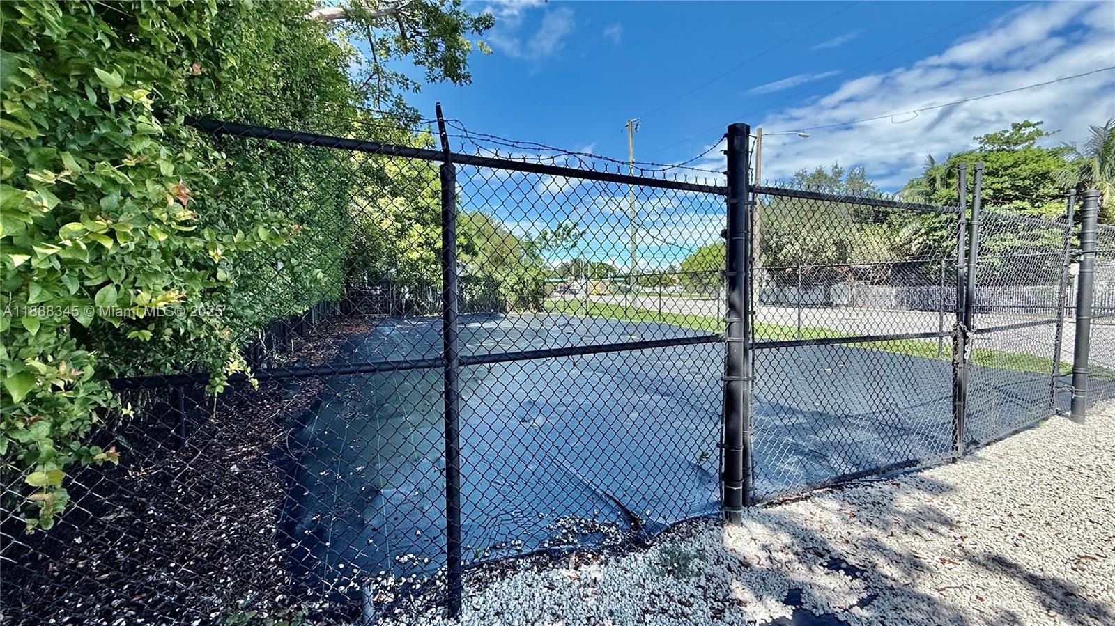 A fenced-in outdoor area with a dark ground covering and gravel border — 6050 N Miami Ave, Miami FL 33137, MIAMI, FL