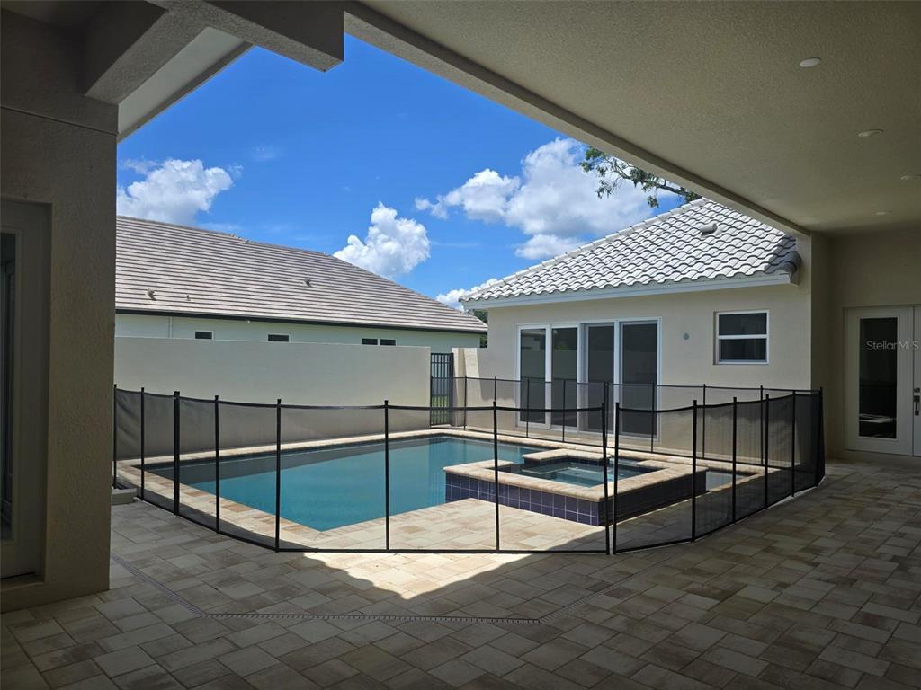 A swimming pool and spa with a safety fence are located on a paved patio — 136 NEW LEATHERWOOD DRIVE, PALM COAST, FL
