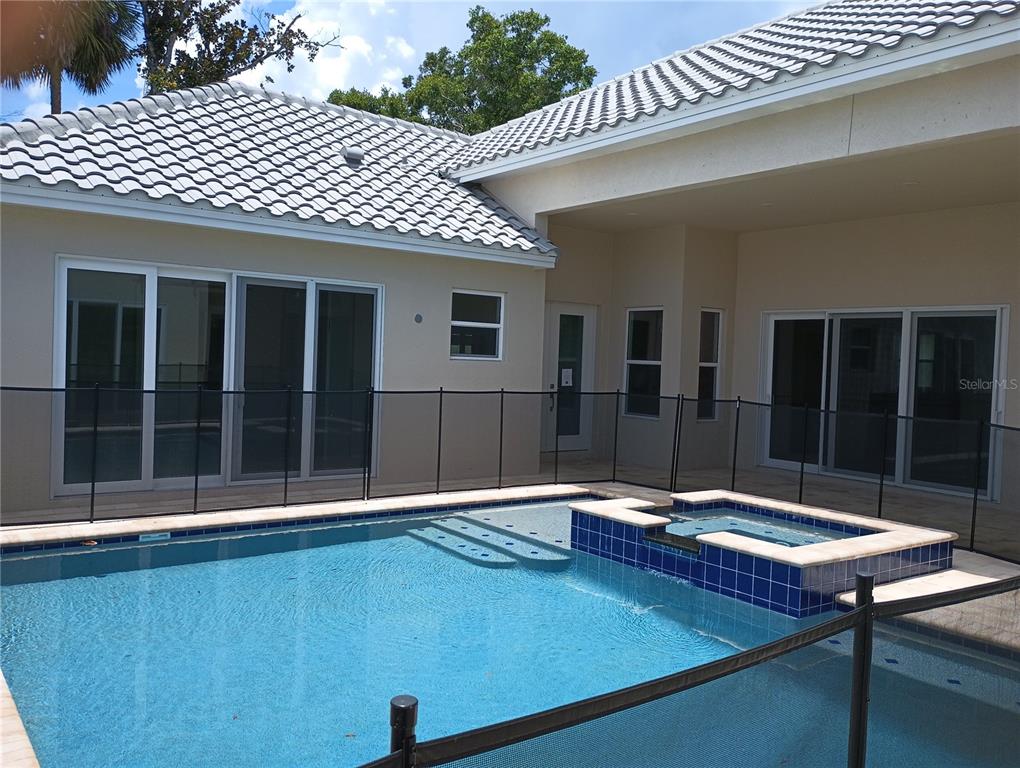 A swimming pool and spa are enclosed by a safety fence outside a residential home — 136 NEW LEATHERWOOD DRIVE, PALM COAST, FL