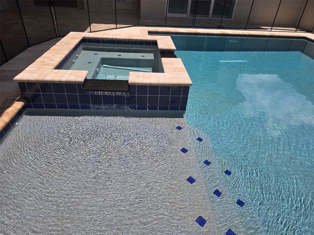 A swimming pool features a raised spa with a spillover edge and tiled steps — 136 NEW LEATHERWOOD DRIVE, PALM COAST, FL