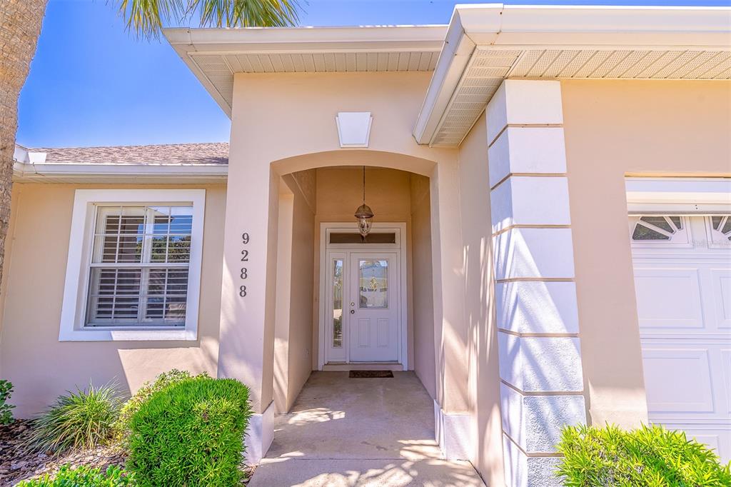 The exterior of a beige house features a covered entryway and a white front door — 9288 SW 93RD CIRCLE, OCALA, FL