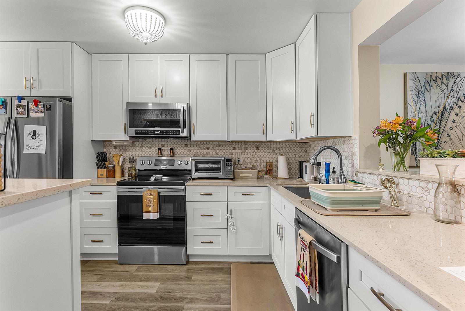 A kitchen features white cabinets, stainless steel appliances, a hexagonal tile backsplash, and quartz countertops — 10110 Cedar Point Boulevard # 203, Boynton Beach FL 33437, BOYNTON BEACH, FL