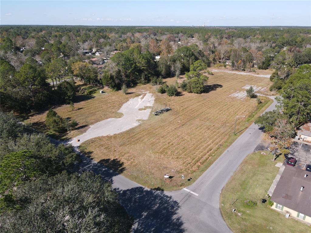 An aerial view shows a large, vacant grassy lot with concrete pads and surrounding trees — 6256 NW 23RD TERRACE, GAINESVILLE, FL