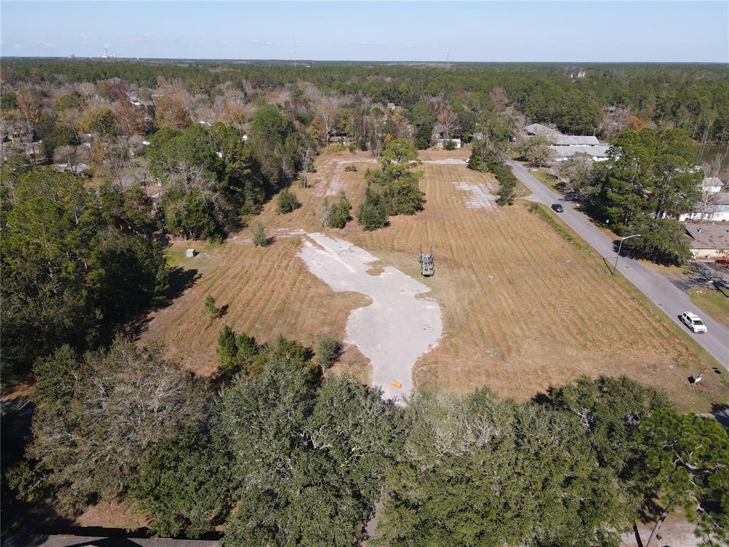 An aerial view shows a large, cleared vacant lot with concrete foundations and surrounding trees — 6256 NW 23RD TERRACE, GAINESVILLE, FL