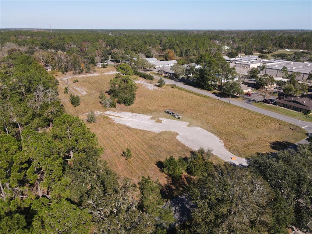 An aerial view shows a large, cleared rectangular lot with patches of concrete and surrounding trees — 6256 NW 23RD TERRACE, GAINESVILLE, FL