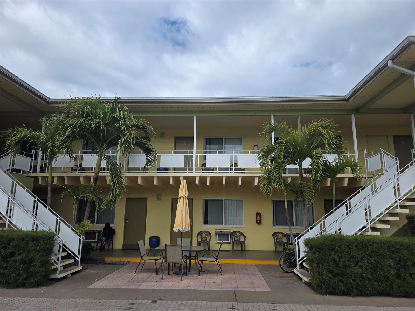 A two-story yellow motel building features exterior staircases, balconies, and a central patio area — 911 N Federal Highway # 205, FL 33460, FL