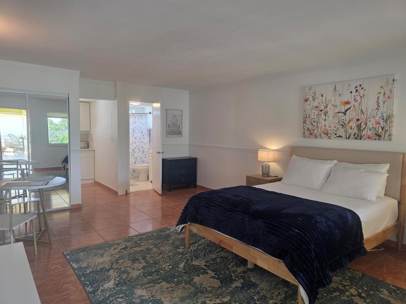 A bedroom with a queen bed, tiled floors, an area rug, and an attached bathroom — 911 N Federal Highway # 205, FL 33460, FL