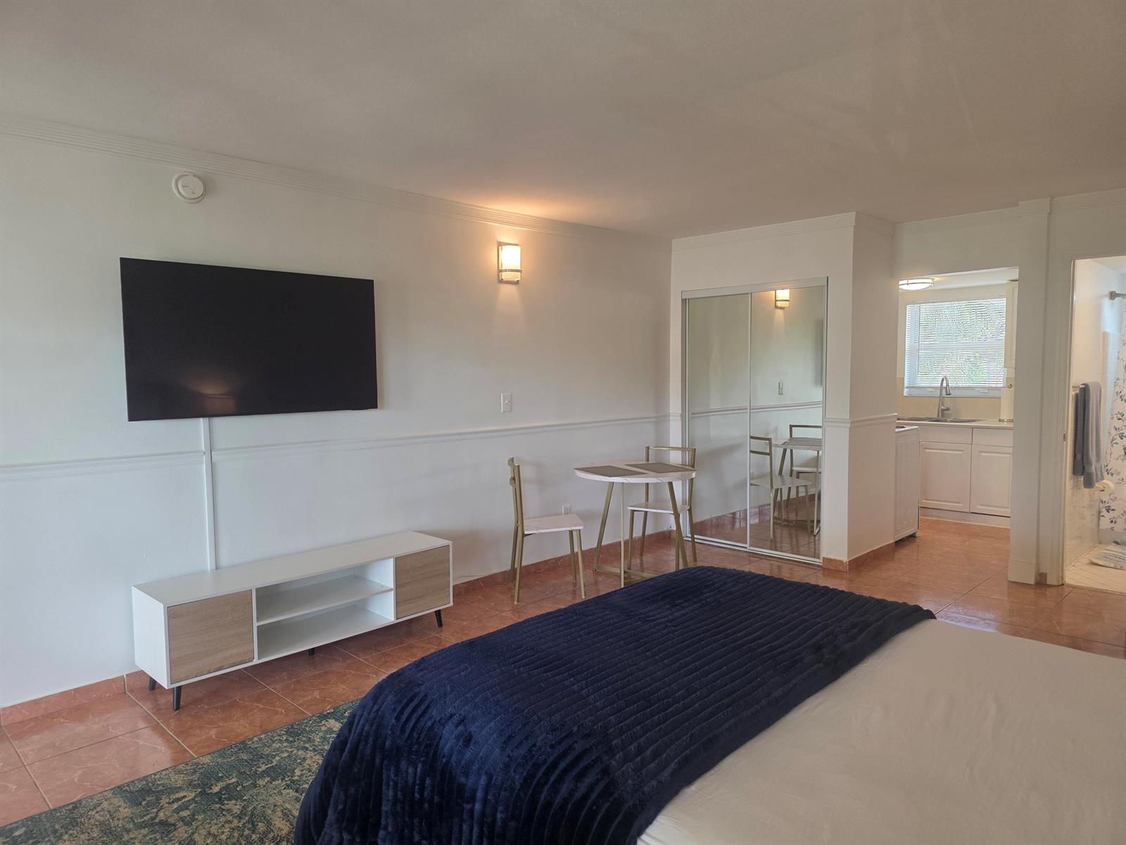 A bedroom with a television, small dining table, mirrored closet, and an adjacent kitchenette — 911 N Federal Highway # 205, FL 33460, FL