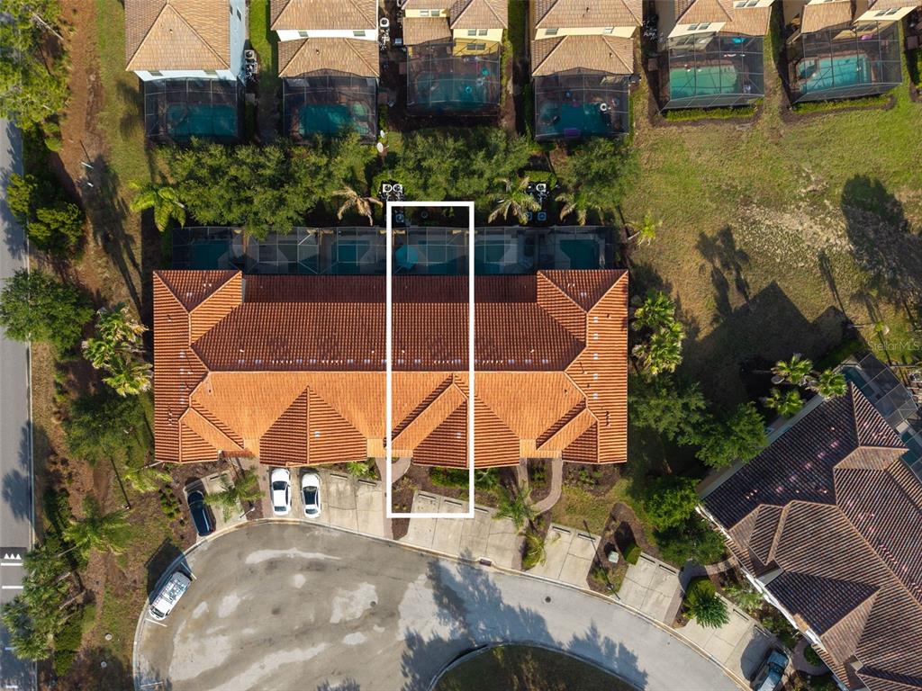 An aerial view shows a townhome unit highlighted within a multi-unit building with pools — 4799 TERRASONESTA DRIVE, DAVENPORT, FL
