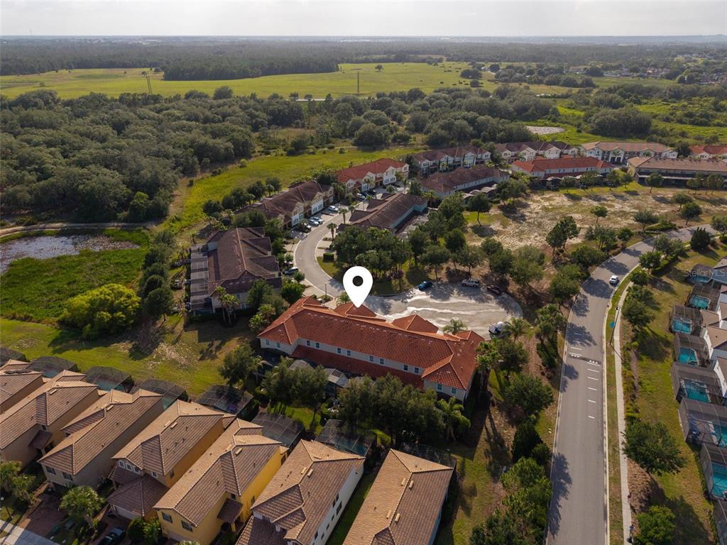 An aerial view shows a residential neighborhood with multi-story townhomes, paved roads, and surrounding green space — 4799 TERRASONESTA DRIVE, DAVENPORT, FL