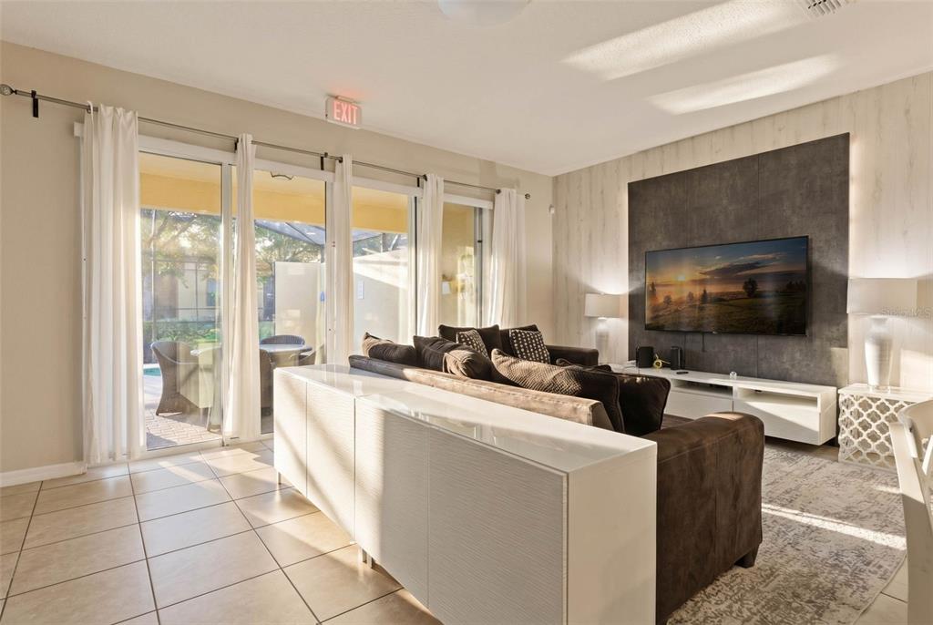 A living room features a dark sofa, a white console table, and a wall-mounted television — 4799 TERRASONESTA DRIVE, DAVENPORT, FL