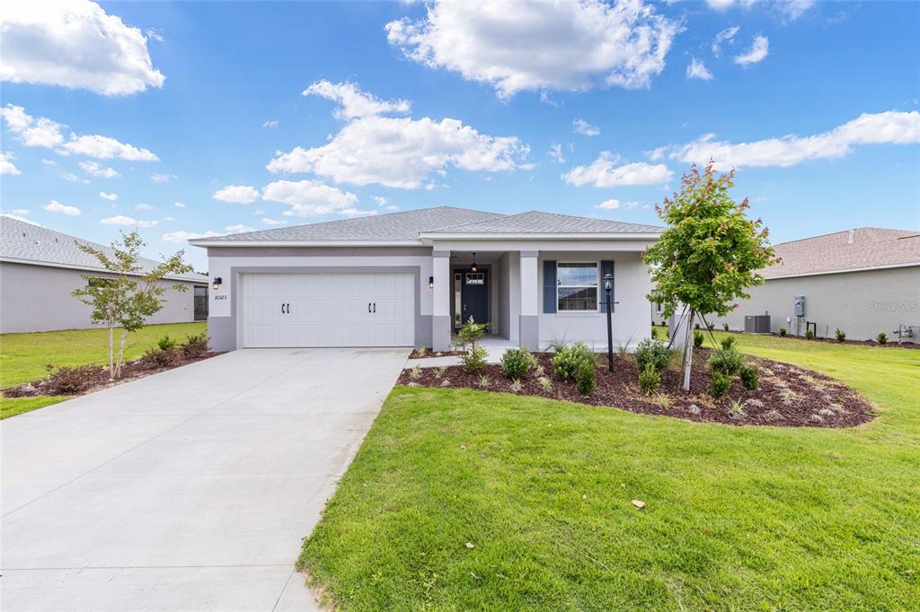 A single-story suburban house features a two-car garage, a covered entryway, and a landscaped yard — 10323 SW 105TH TERRACE, OCALA, FL