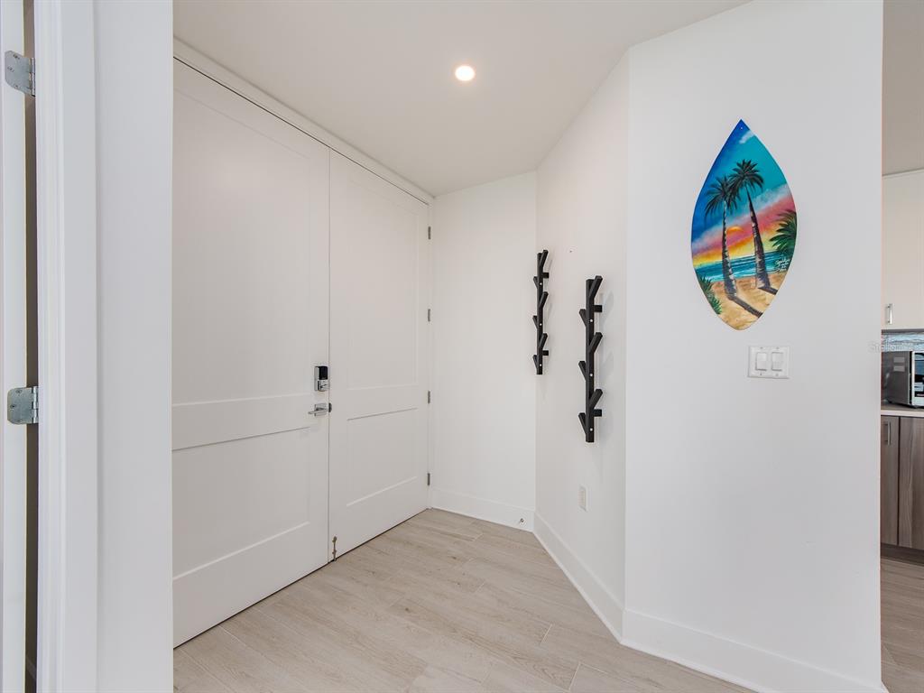 An entryway features white double doors, light wood-look flooring, and wall-mounted coat racks — 15 AVALON STREET UNIT 701, CLEARWATER BEACH, FL