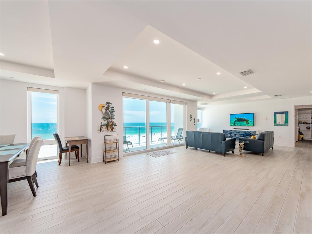 An open-concept living and dining area features light wood-look flooring and floor-to-ceiling ocean views — 15 AVALON STREET UNIT 701, CLEARWATER BEACH, FL