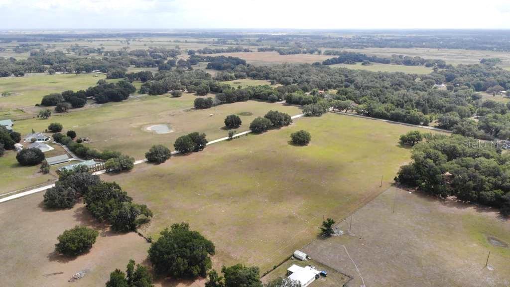 An aerial view shows a large, grassy rural property with scattered trees and several buildings — 5780 CR 569, CENTER HILL, FL