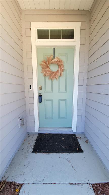 A light blue front door with a wreath sits on a concrete porch — 36 RYARBOR DRIVE, PALM COAST, FL
