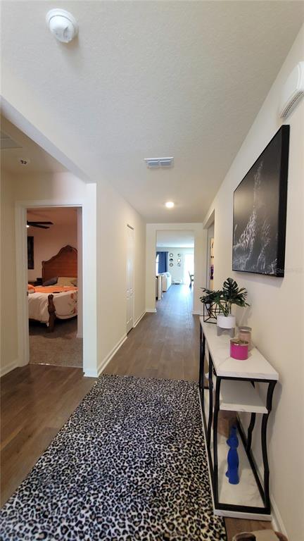 A hallway with wood-look flooring leads to a bedroom and a distant living area — 36 RYARBOR DRIVE, PALM COAST, FL