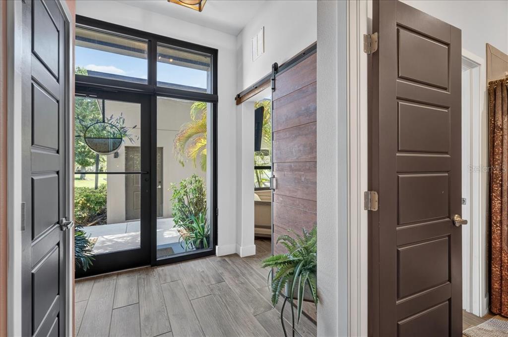 An entryway features wood-look tile flooring, a glass-paned front door, and a sliding barn door — 4134 GAUGE LINE LOOP, TAMPA, FL