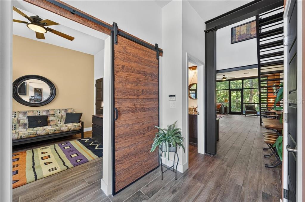 A hallway with wood-look tile flooring features a sliding barn door and a metal staircase — 4134 GAUGE LINE LOOP, TAMPA, FL