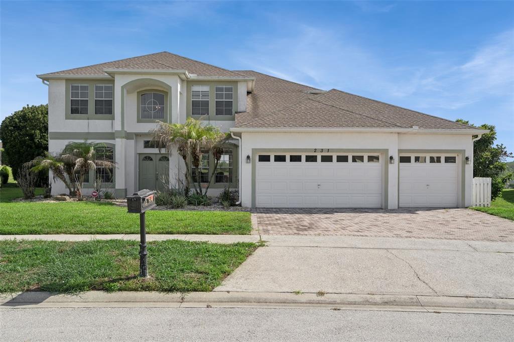 A two-story suburban house features a three-car garage, a paved driveway, and a front lawn — 231 BELFRY DRIVE, DAVENPORT, FL