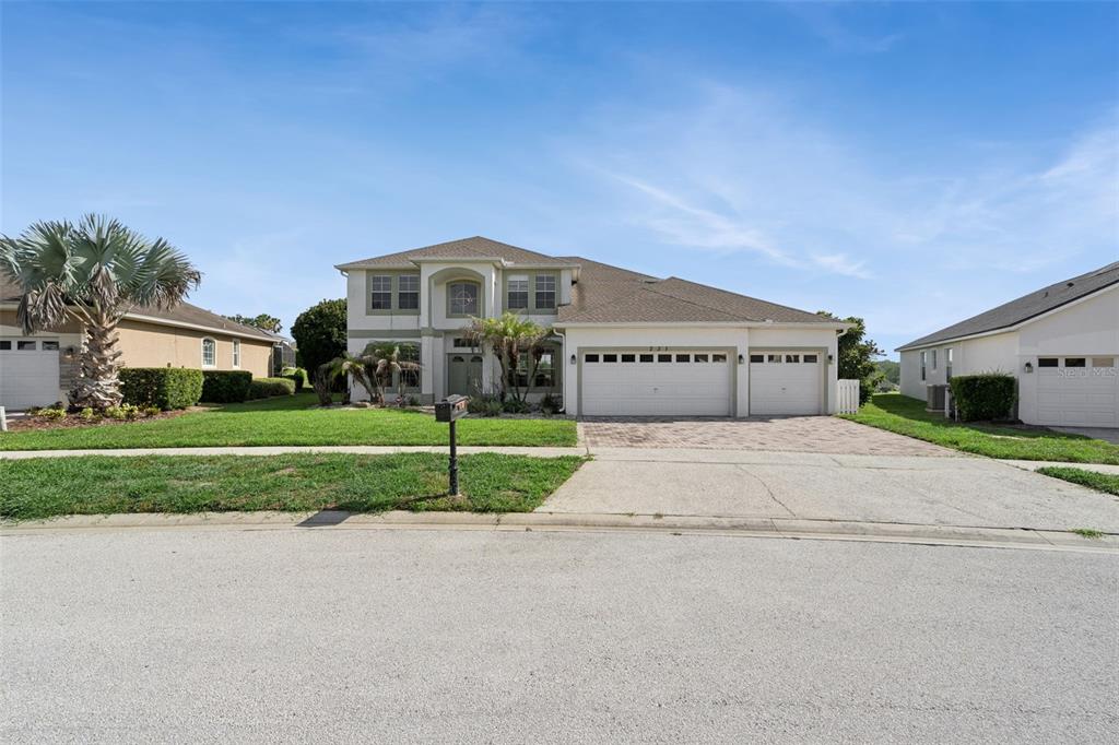 A two-story suburban house with a three-car garage and a paved driveway — 231 BELFRY DRIVE, DAVENPORT, FL