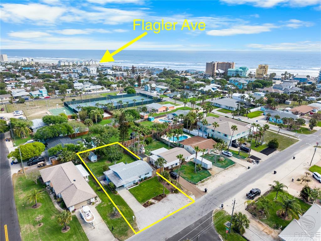 An aerial view shows a single-story house outlined in yellow near a coastal beach town — 702 OCEAN AVENUE, NEW SMYRNA BEACH, FL