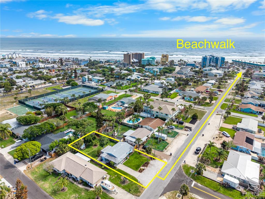 An aerial view shows a residential property outlined in yellow near a coastal beach — 702 OCEAN AVENUE, NEW SMYRNA BEACH, FL