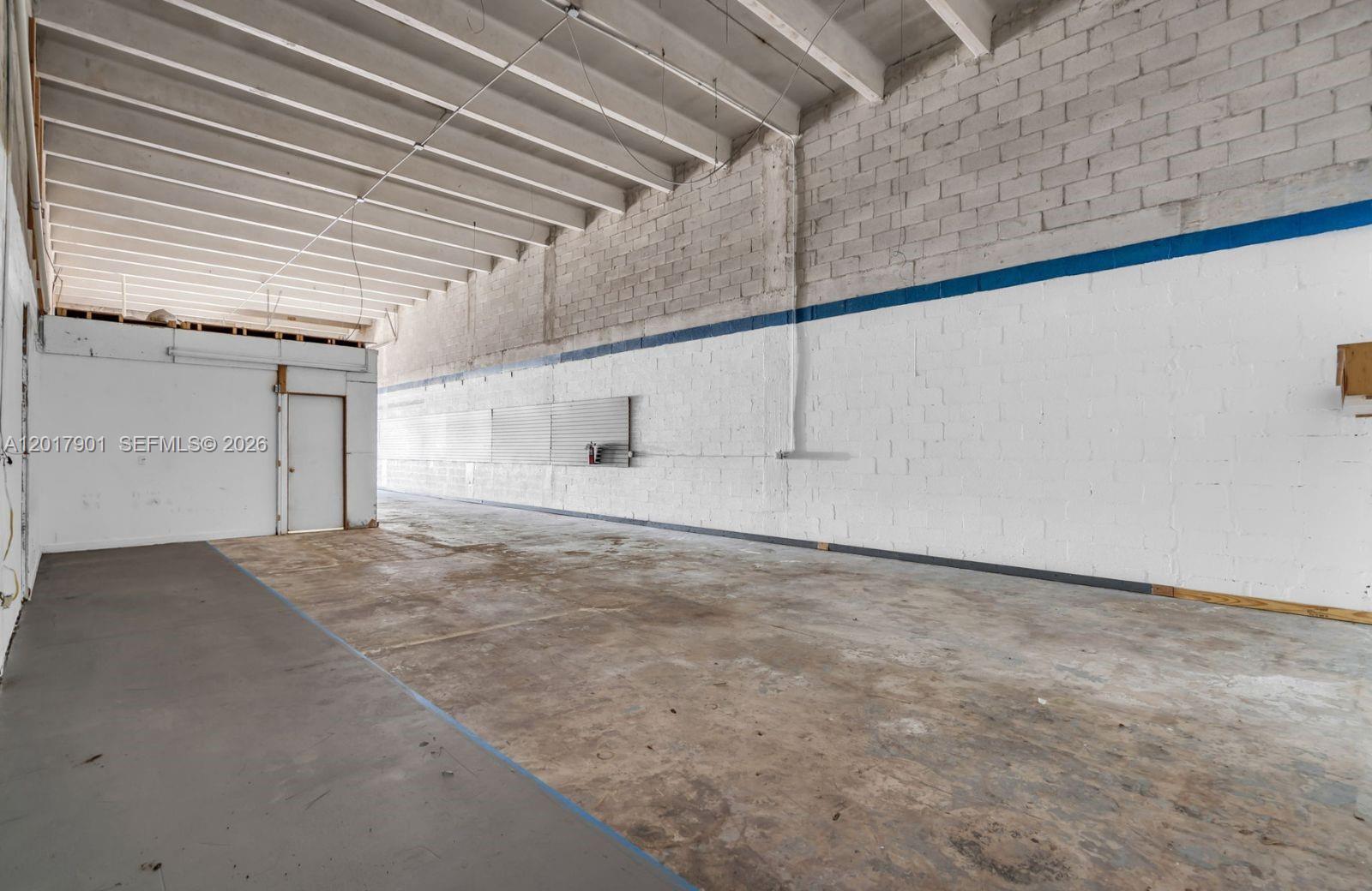 An empty industrial warehouse space features exposed ceiling beams and white painted concrete block walls — 6409 NW 82nd Ave # 6423, Medley FL 33166, MEDLEY, FL