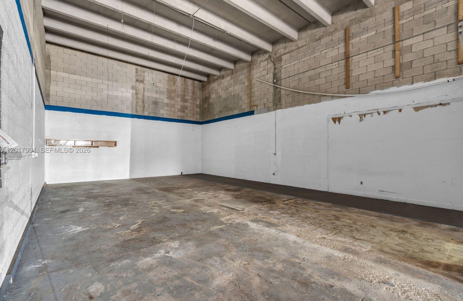 An empty industrial warehouse space features concrete block walls, a high ceiling, and stained flooring — 6409 NW 82nd Ave # 6423, Medley FL 33166, MEDLEY, FL