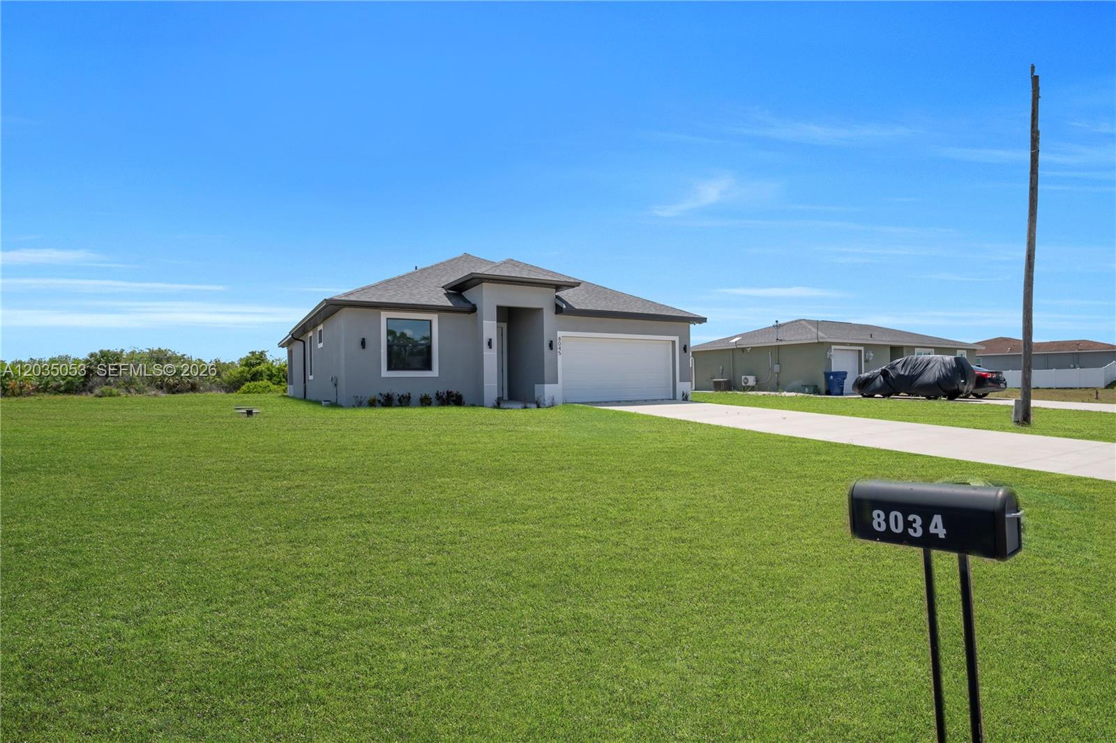 A gray single-story house with a two-car garage sits on a large grassy lot — 8045 Buttercup Cir, La Belle FL 33935, LA BELLE, FL
