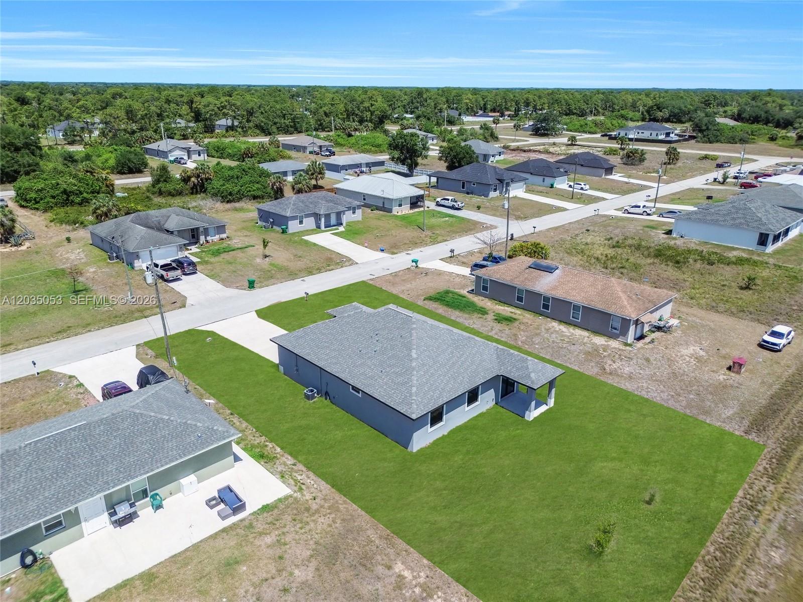 An aerial view shows several single-story suburban houses with driveways and lawns under a blue sky — 8045 Buttercup Cir, La Belle FL 33935, LA BELLE, FL