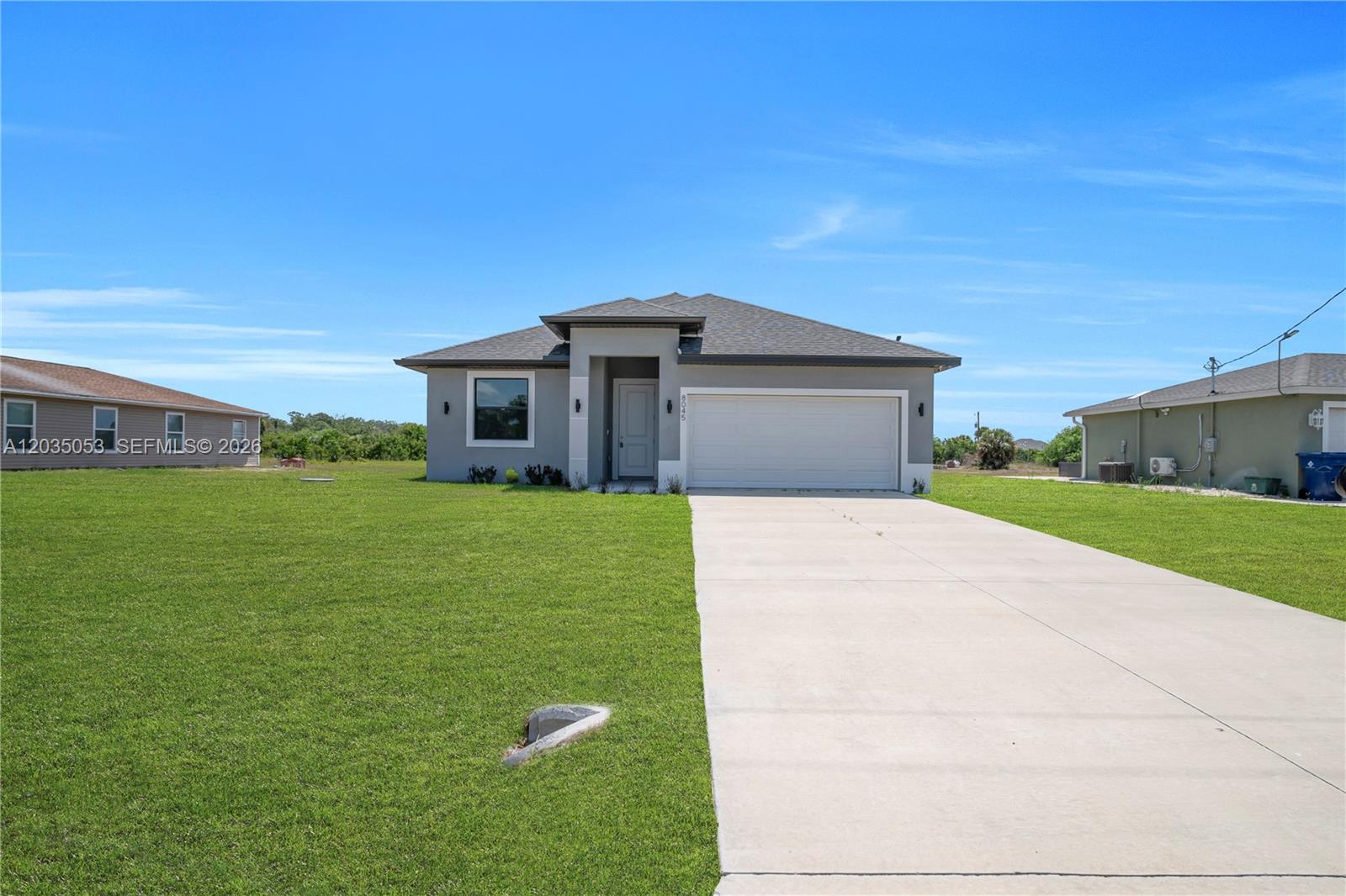 A single-story gray house with a two-car garage and a concrete driveway — 8045 Buttercup Cir, La Belle FL 33935, LA BELLE, FL
