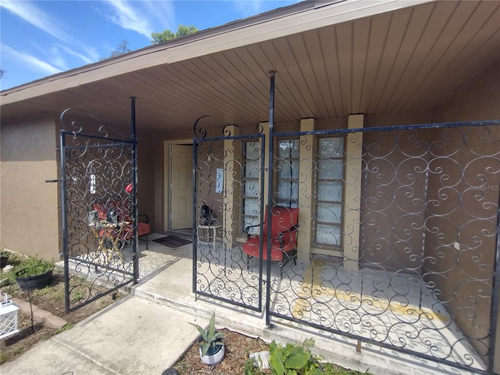 A covered front porch features decorative black wrought iron railings and a concrete walkway — 2419 APPIAN AVENUE, SPRING HILL, FL