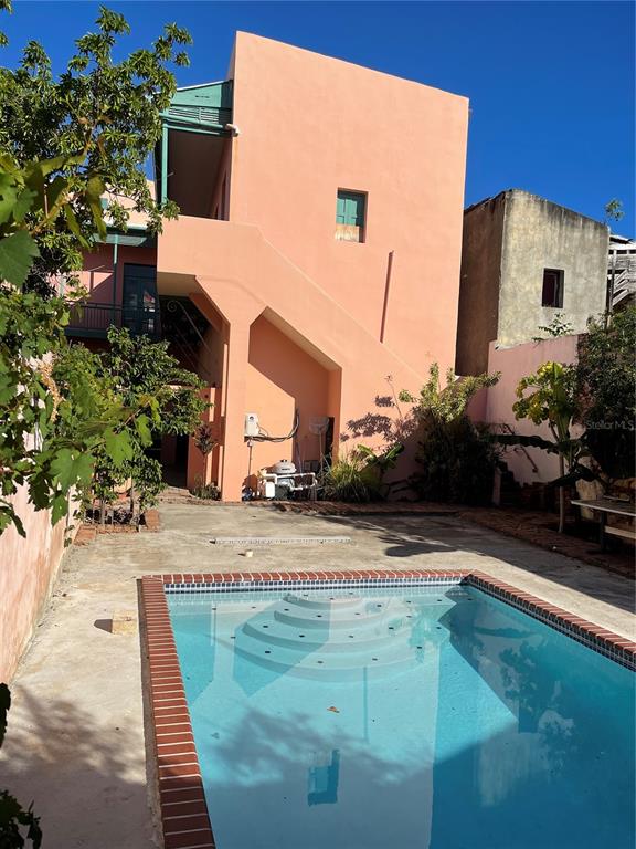 A peach-colored multi-story building stands behind a rectangular swimming pool with a brick border — 31-33 MARINA STREET, PONCE, PR