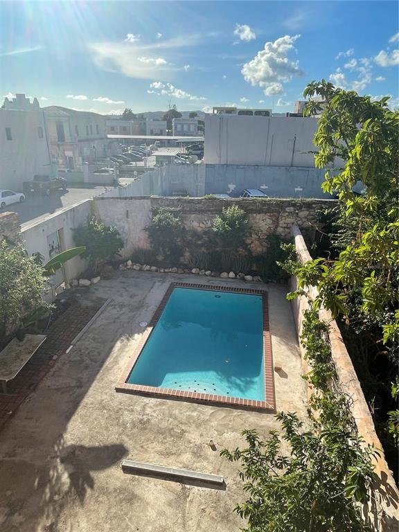 An outdoor rectangular swimming pool is set in a concrete patio surrounded by stone walls — 31-33 MARINA STREET, PONCE, PR