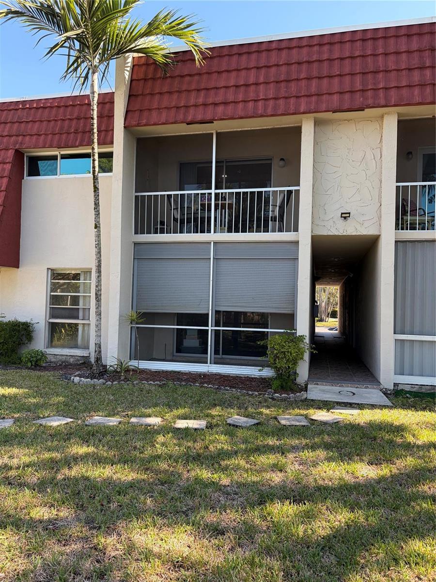 A two-story building exterior features a ground-floor screened patio with shutters and an upper balcony — 21 Jacaranda Drive # 121, Plantation FL 33324, PLANTATION, FL