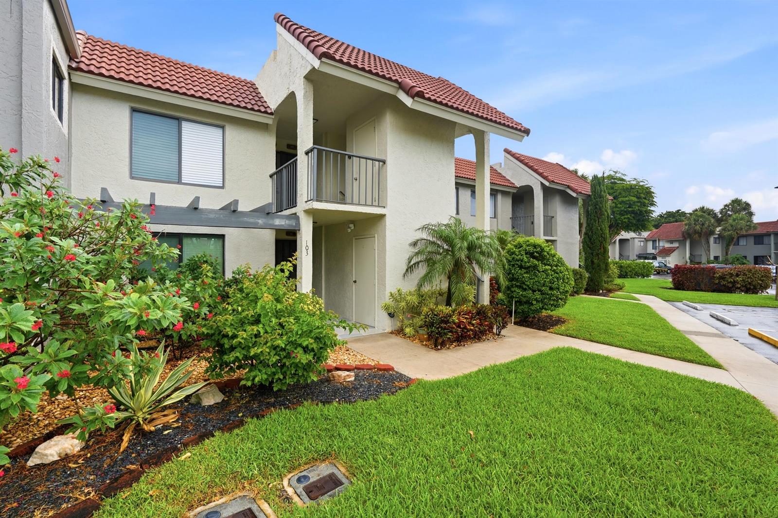 A two-story apartment building exterior with a tiled roof, stucco walls, and a landscaped yard — 5500 Fairway Park Drive # 103, Boynton Beach FL 33437, BOYNTON BEACH, FL